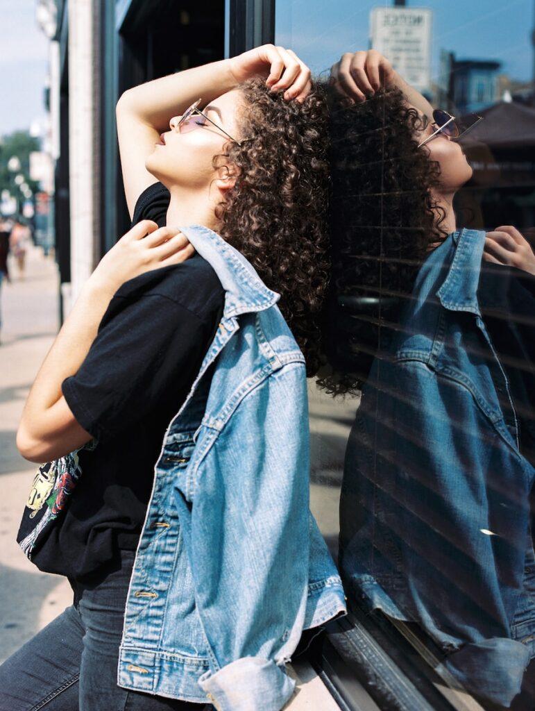 woman leaning on glass window with a denim shirt