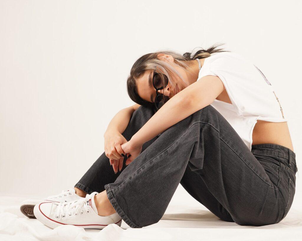 woman in white tank top and blue denim jeans sitting on white floor