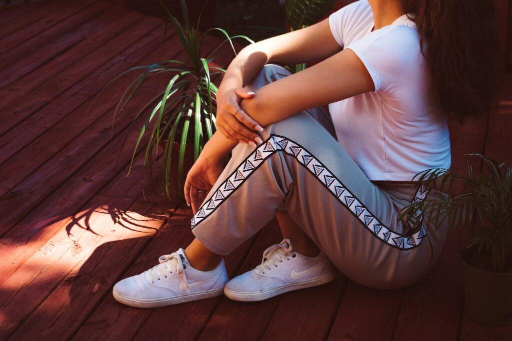 a woman sitting on a wooden deck next to a potted plant